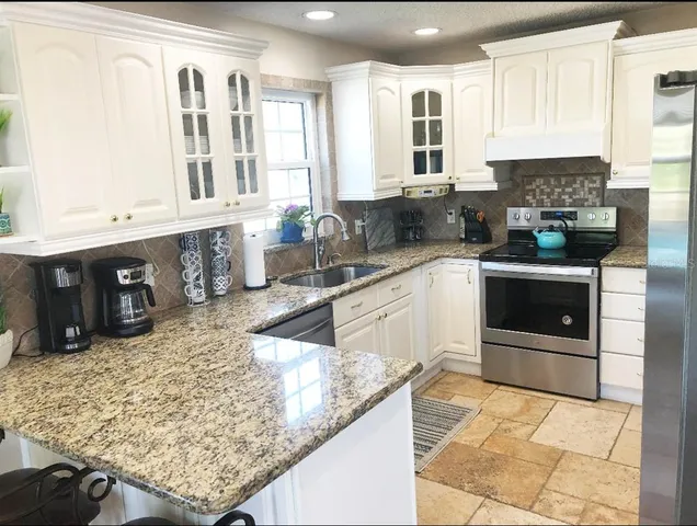 a kitchen with stainless steel appliances granite countertop a sink counter space and a stove