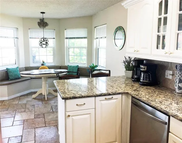 a kitchen with granite countertop a sink a stove and cabinets