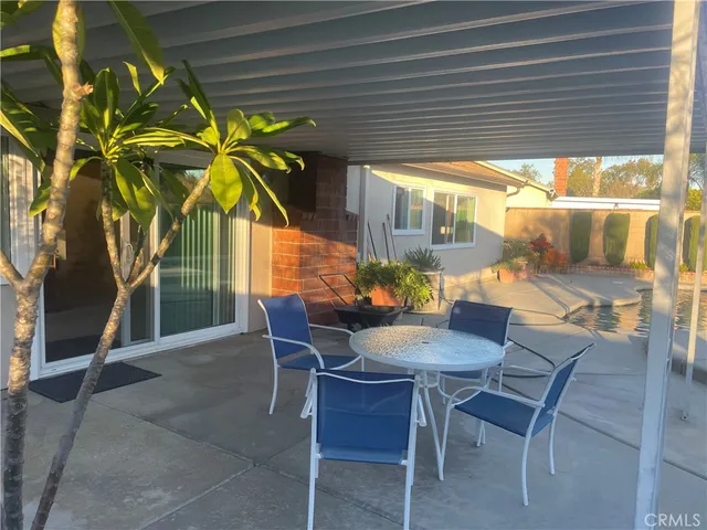 a patio with table and chairs and potted plants