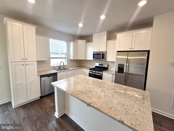 a kitchen with granite countertop white cabinets and stainless steel appliances