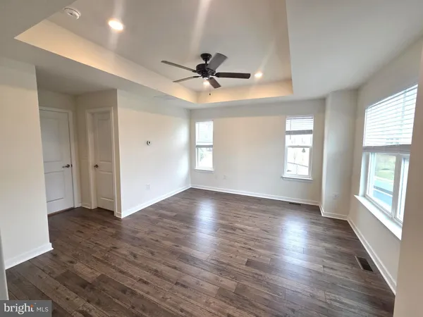 an empty room with wooden floor chandelier fan and windows