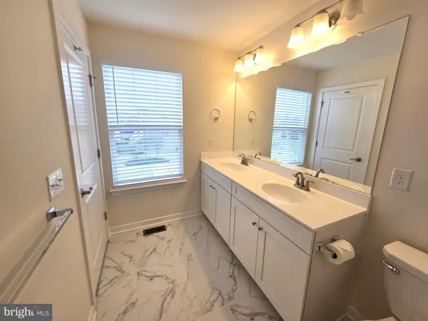 a bathroom with a double vanity sink toilet mirror and bathtub