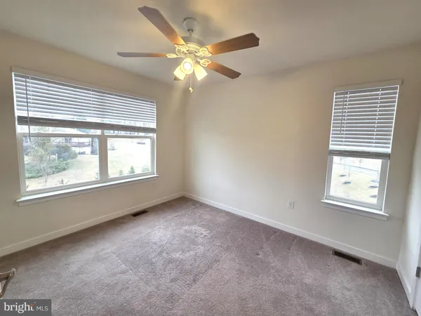 an empty room with windows and fan