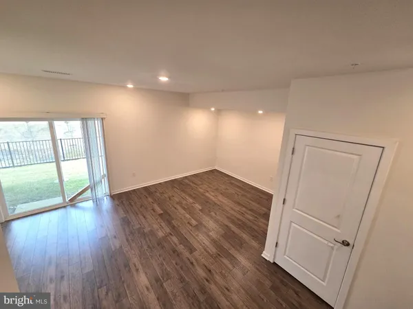 a view of an empty room with wooden floor and windows