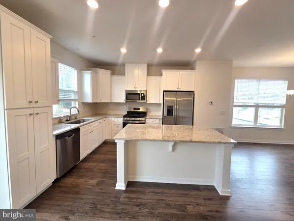 a large kitchen with stainless steel appliances granite countertop a stove a sink dishwasher and a microwave oven with wooden floor