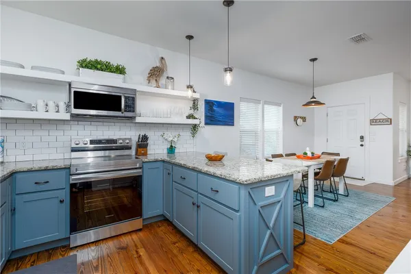 a kitchen with stainless steel appliances granite countertop a stove and white cabinets