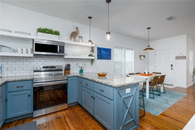 a kitchen with stainless steel appliances granite countertop a stove and white cabinets