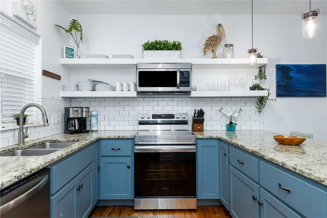 a kitchen with stainless steel appliances granite countertop a sink a stove and cabinets