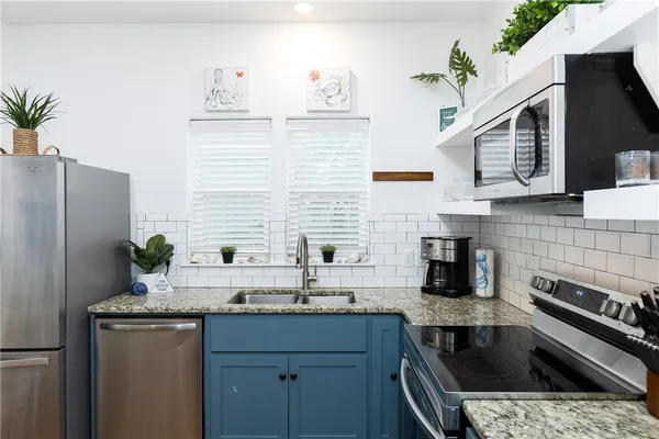 a kitchen with stainless steel appliances granite countertop a sink and a refrigerator