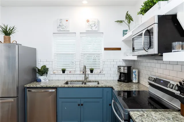 a kitchen with stainless steel appliances granite countertop a sink and a refrigerator