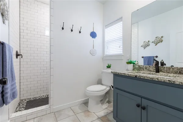 a bathroom with a granite countertop sink a toilet and shower