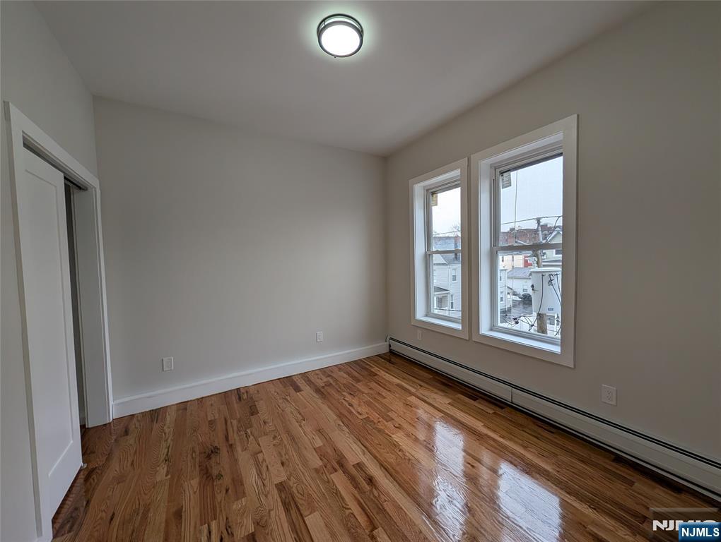 69 Howe Avenue, Unit 9 Passaic, NJ 07055 - Photo 12 of 20 a view of an empty room with wooden floor and a window