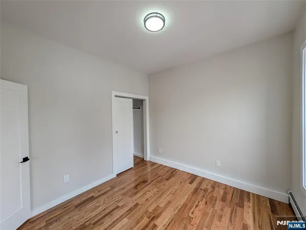 a view of an empty room with wooden floor and closet