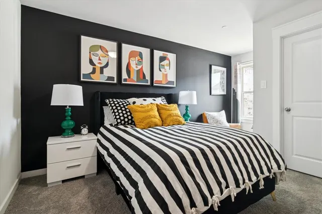 a bedroom with a bed and a lamp on dresser