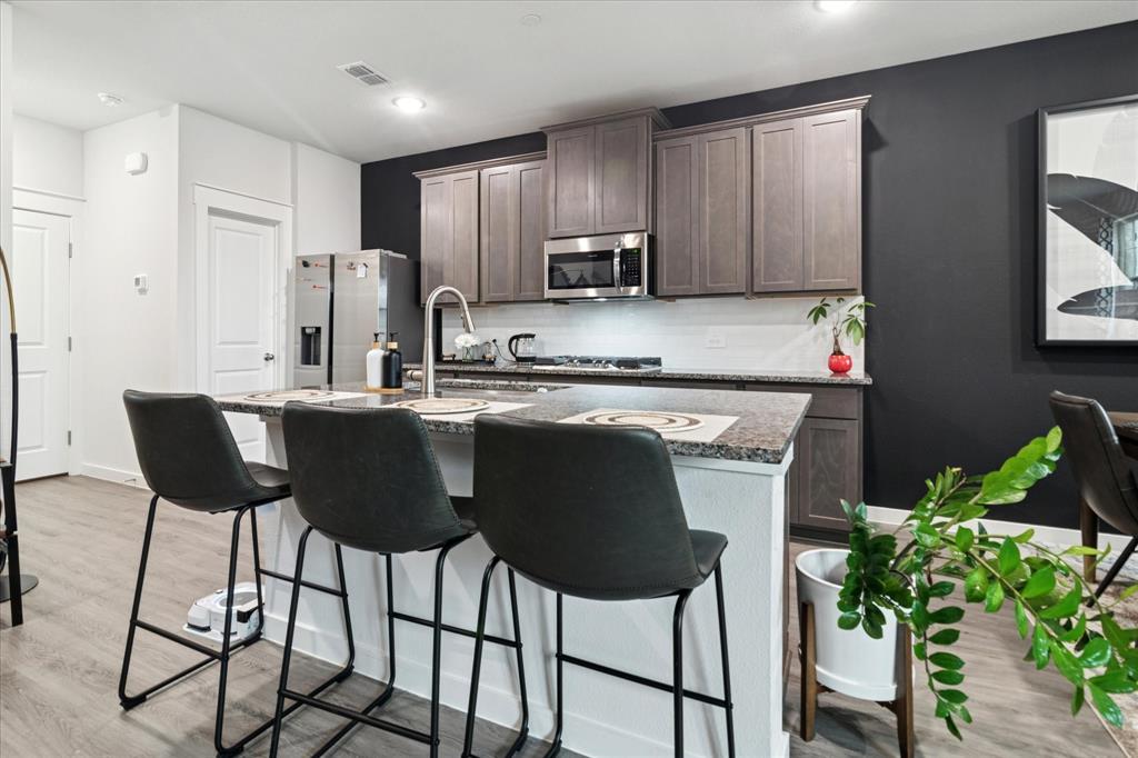 3047 Tenor Way Sachse, TX 75048 - Photo 4 of 17 a kitchen with stainless steel appliances a dining table chairs refrigerator and sink