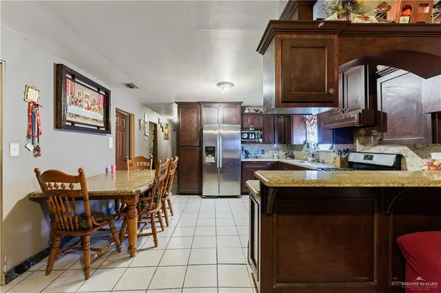 a kitchen with stainless steel appliances granite countertop a table chairs and a refrigerator