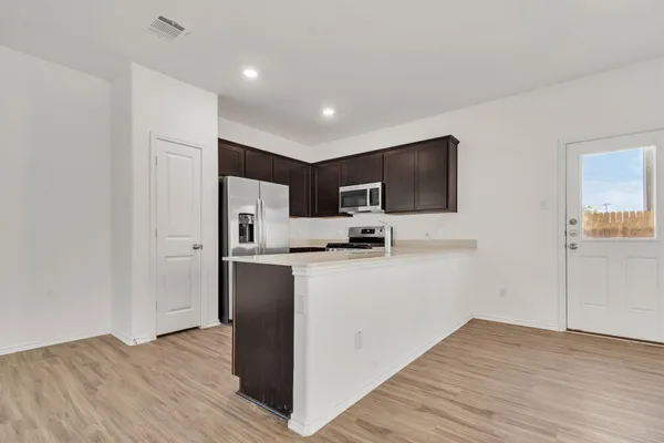 a view of kitchen with stainless steel appliances refrigerator stove microwave and cabinets