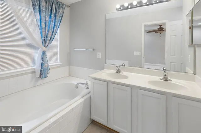 a bathroom with a sink a bathtub a mirror a vanity and a shower