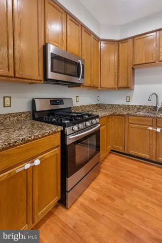 a kitchen with granite countertop wooden cabinets stainless steel appliances and a sink