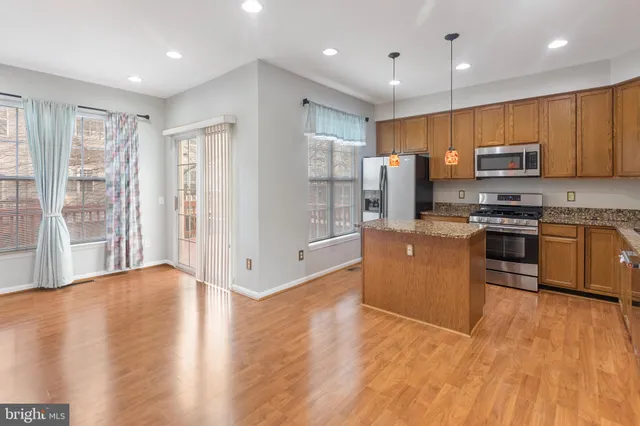 a kitchen with stainless steel appliances granite countertop a refrigerator a stove top oven a sink and dishwasher with wooden floor