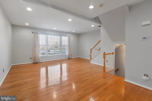 a view of an empty room with wooden floor and stairs