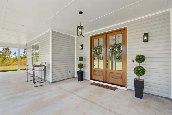 a living room with stainless steel appliances furniture wooden floor and a kitchen view