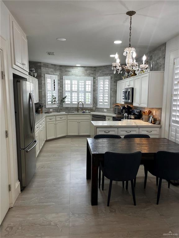406 Rio Grande Drive Mission, TX 78572 - Photo 7 of 27 Kitchen with a peninsula, black appliances, hanging light fixtures, a chandelier, and white cabinets