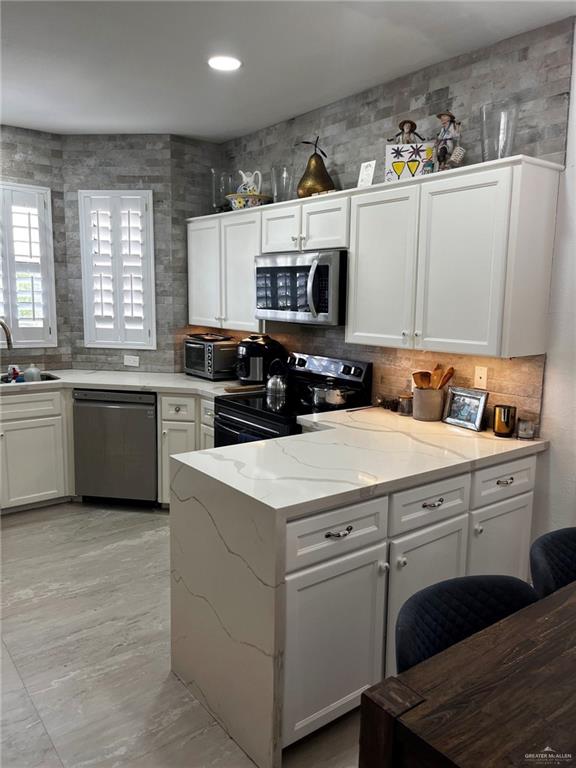406 Rio Grande Drive Mission, TX 78572 - Photo 8 of 27 Kitchen featuring white cabinetry, tasteful backsplash, appliances with stainless steel finishes, light stone countertops, and recessed lighting