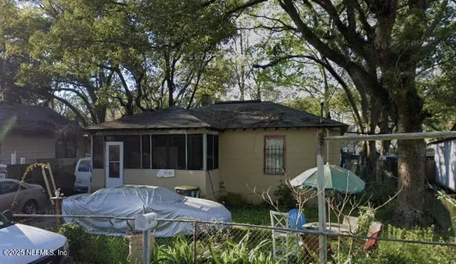 a backyard of a house with table and chairs under an umbrella