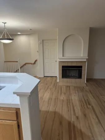 an empty room with wooden floor a fireplace and window