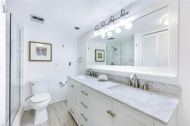 a bathroom with a granite countertop sink mirror vanity and toilet