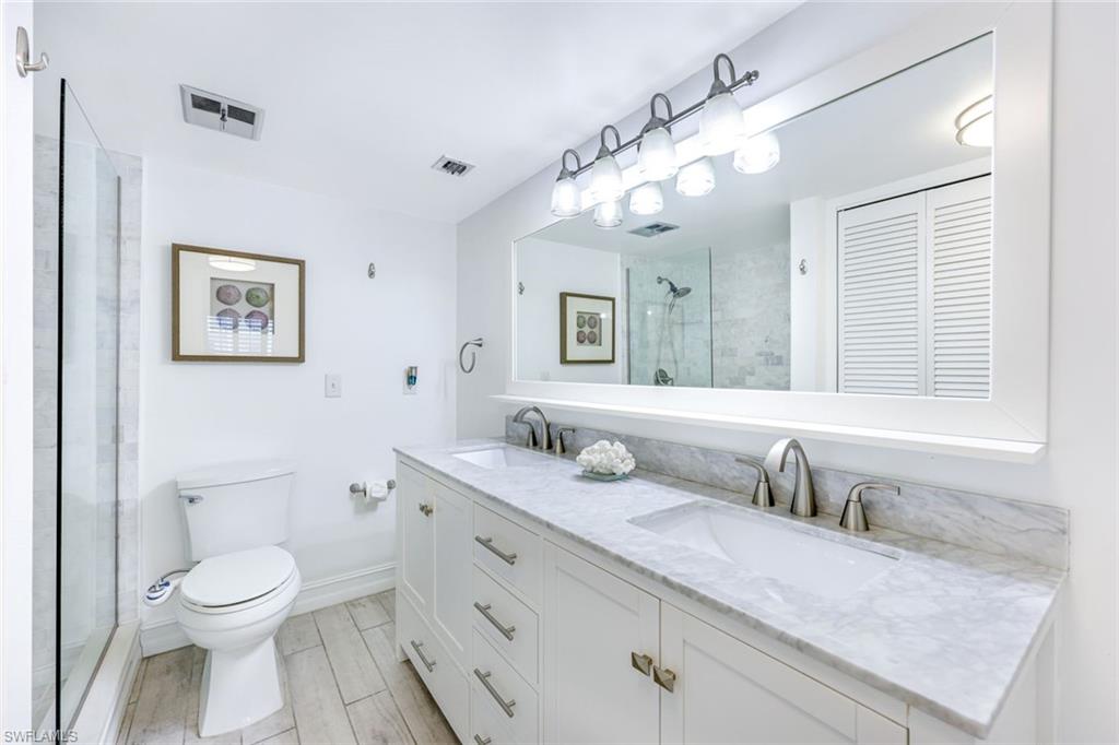766 Central Avenue, Unit 117 Naples, FL 34102 - Photo 11 of 25 a bathroom with a granite countertop sink mirror vanity and toilet