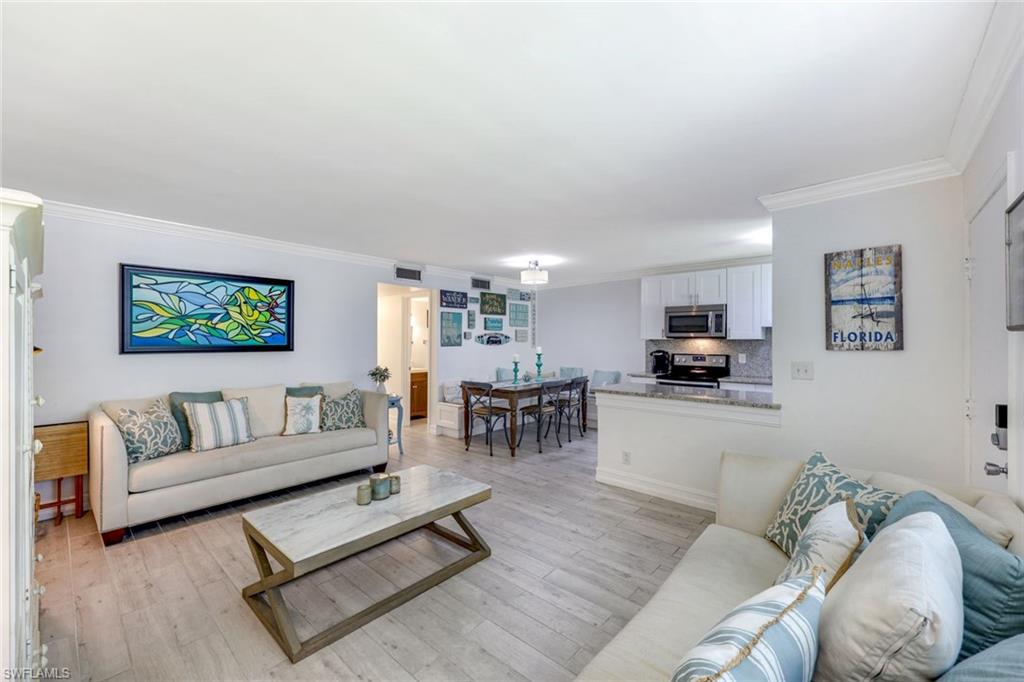 766 Central Avenue, Unit 117 Naples, FL 34102 - Photo 2 of 25 a living room with furniture and a dining table with kitchen view