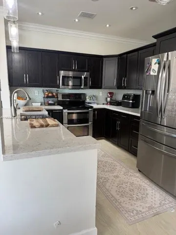 a kitchen with stainless steel appliances wooden cabinets a sink a stove a refrigerator and cabinets