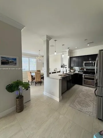 a large white kitchen with stainless steel appliances kitchen island granite countertop a refrigerator and a sink