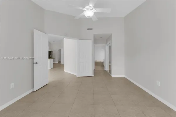a view of an empty room with a chandelier fan