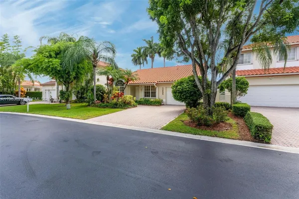 front view of house with a yard and palm trees