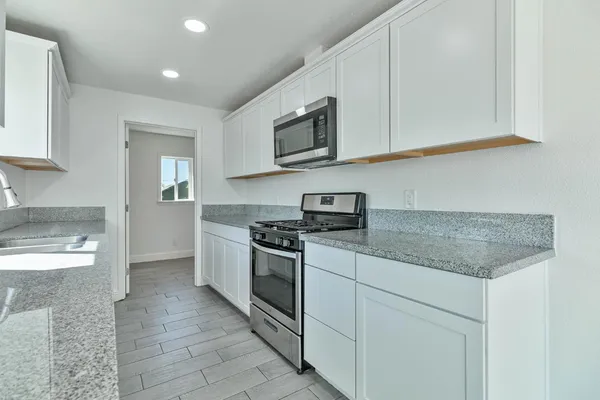 a kitchen with stainless steel appliances granite countertop a stove a sink and a microwave