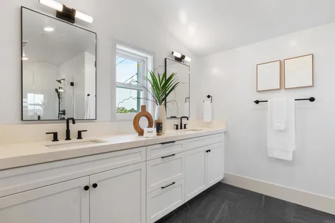 a bathroom with a double vanity sink a mirror and next to a window