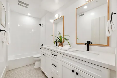 a bathroom with a double vanity sink a toilet and a bathtub