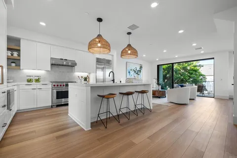 a kitchen with kitchen island stainless steel appliances a dining table and a wooden floor
