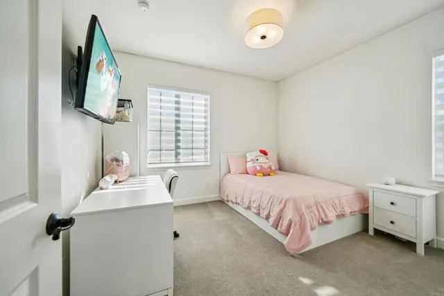 a bedroom with a bed and a flat tv screen on the dresser