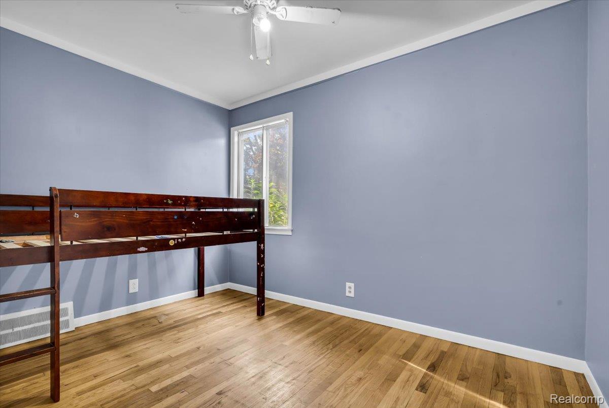 1215 Center Street Inkster, MI 48141 - Photo 17 of 30 Hardwood flooring, painted walls, window with natural light, white ceiling fan with light fixture, and white crown molding