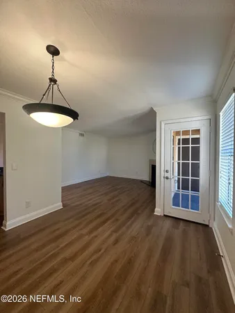 an empty room with wooden floor chandelier and windows