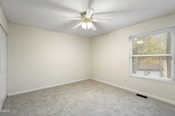 an empty room with a window and a ceiling fan
