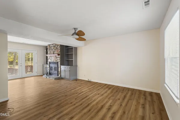a view of an empty room with wooden floor and a window
