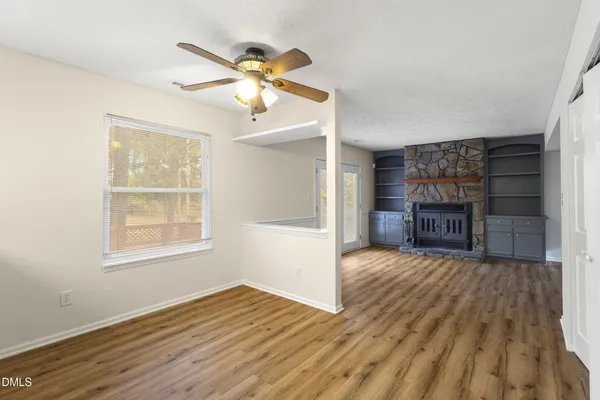 a view of a livingroom with wooden floor a ceiling fan and windows
