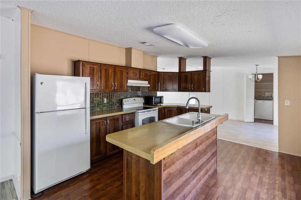 4495 Southeast 150th Street Summerfield, FL 34491 - Photo 62 of 76 a kitchen that has a refrigerator a stove and a sink with wooden floor