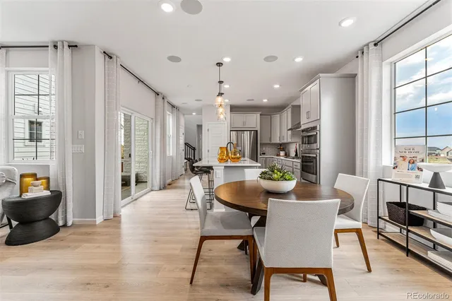 a kitchen with stainless steel appliances granite countertop a refrigerator a oven a stove a sink dishwasher and a dining table with wooden floor