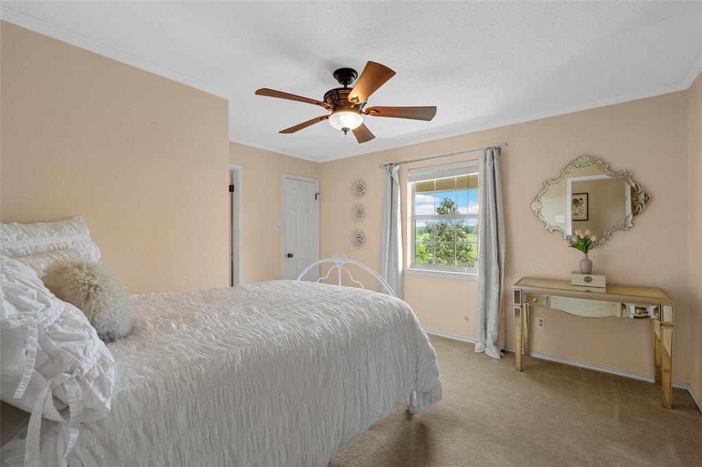743 Stillwater Road Waco, TX 76708 - Photo 20 of 40 a spacious bedroom with a bed and a chandelier